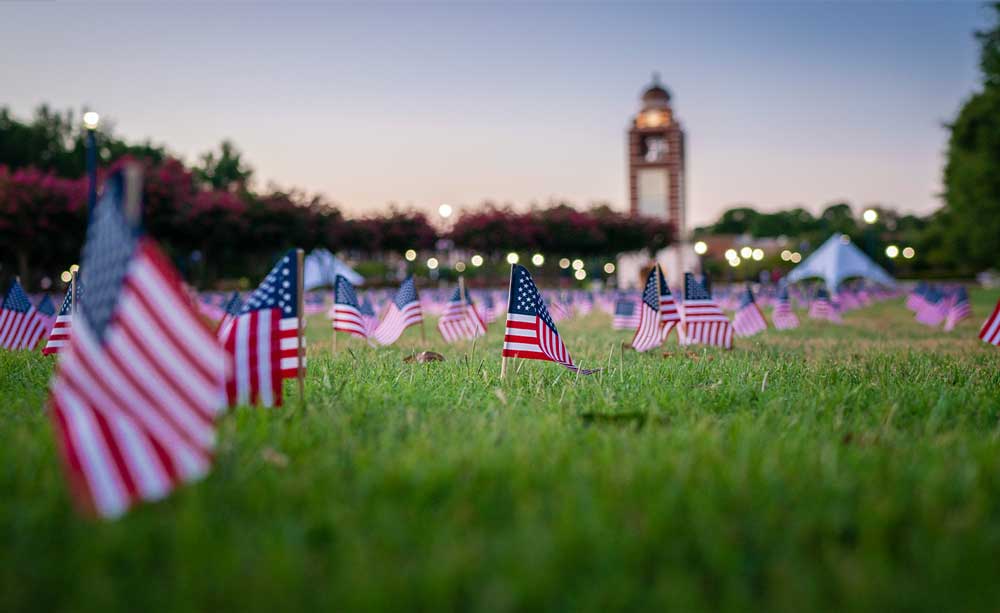 American Flags planted throughout the 91免费福利网 Campus Green with the Bell Tower in the background